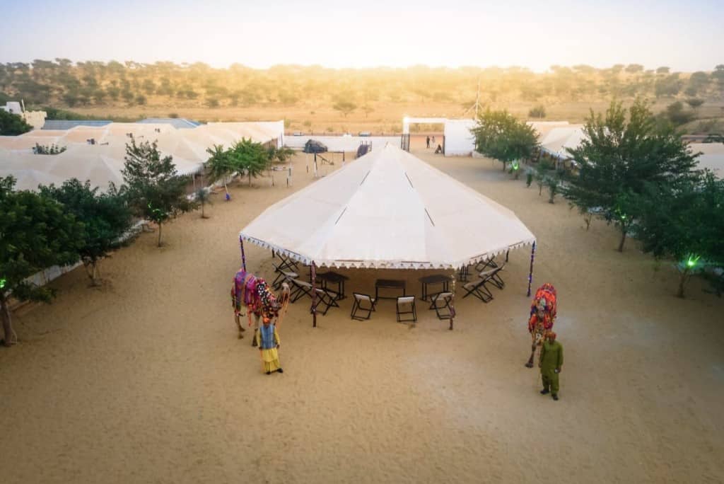 Aerial view of the Jaisalmer desert camp with decorated camels and a central tent