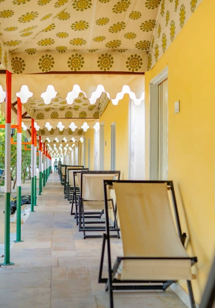 Long covered corridor of yellow camp rooms with lounge chairs