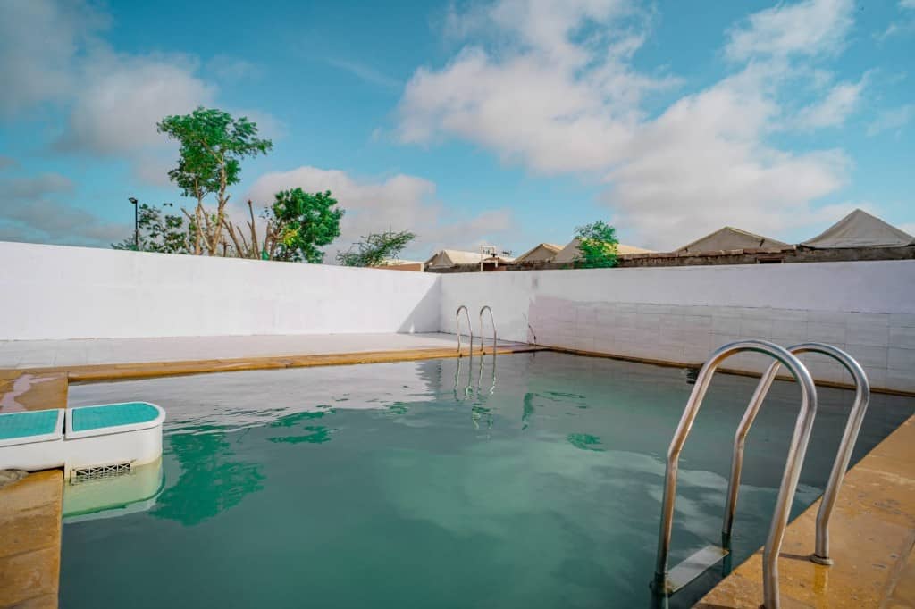 Swimming pool at the Jaisalmer desert camp with tents beyond the wall