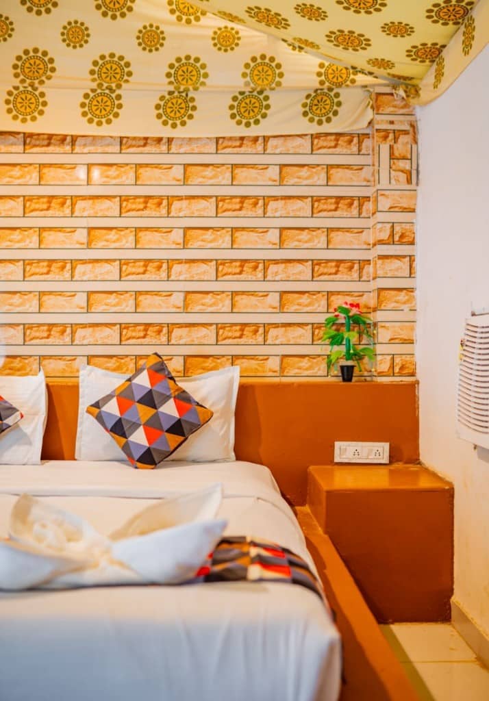 Close view of a made bed in a tent room with a brick headboard wall