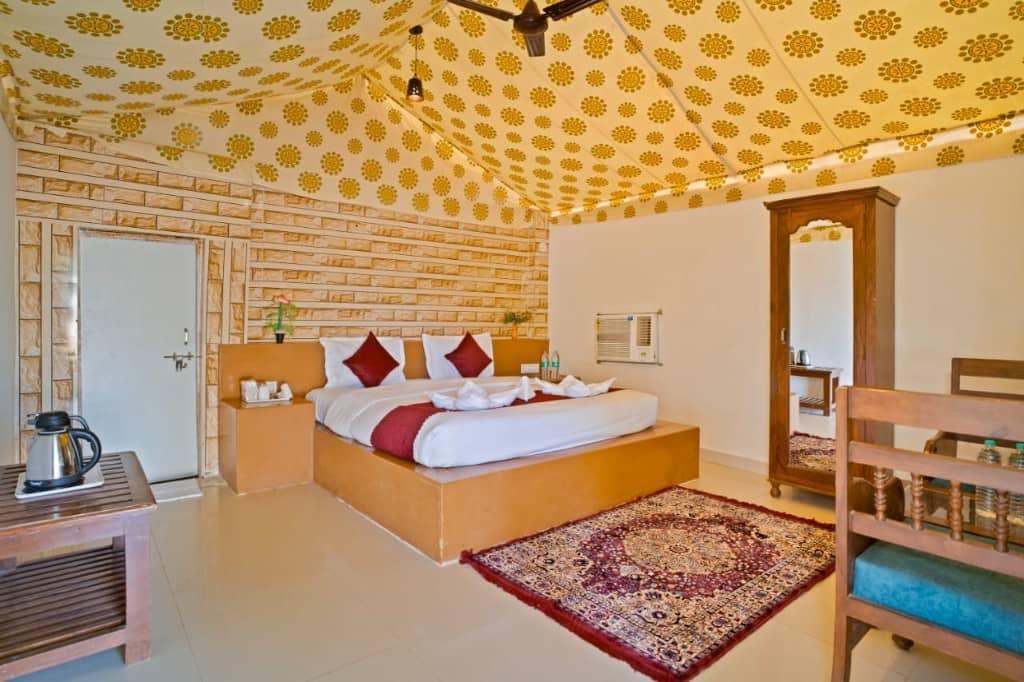 Tent room with a kettle, red bed runner, rug and wardrobe