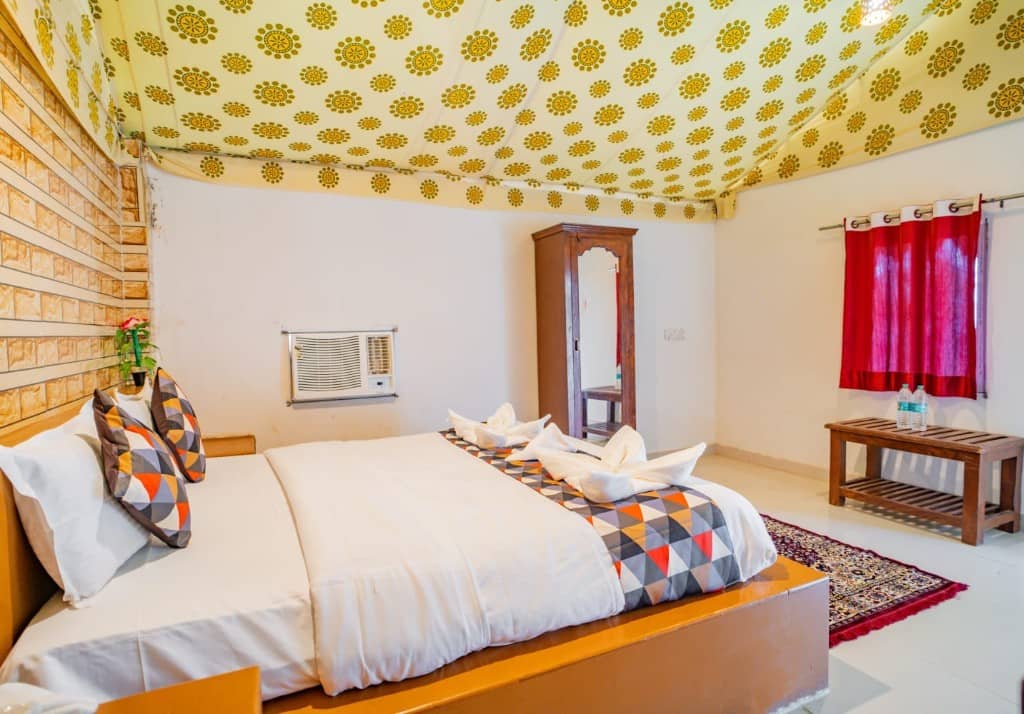 Tent room with red curtains, wooden chairs and a geometric bed runner