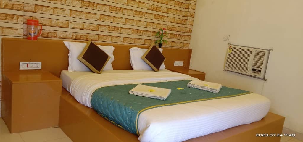 Tent room with a teal bed runner, brick wall and window air conditioner