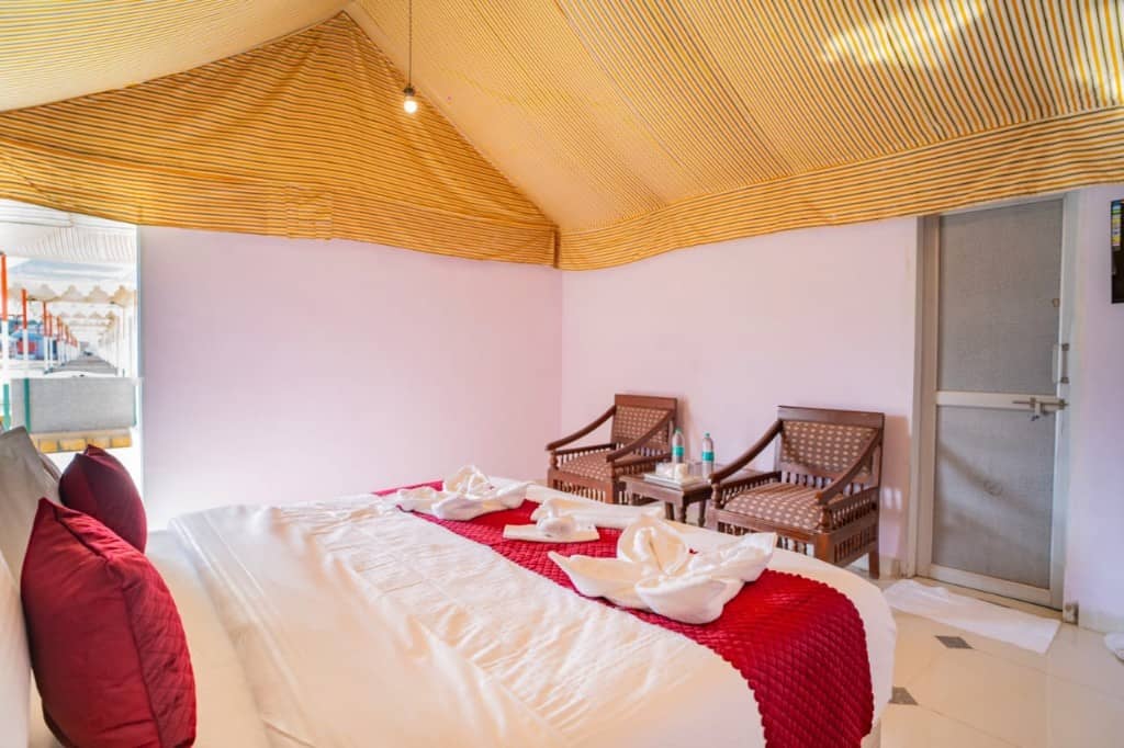 Tent room with a teal patterned wall, red cushions and an open door to the camp