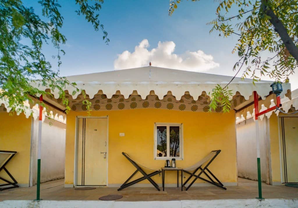 Yellow camp cottage with a scalloped tent roof, porch and two lounge chairs