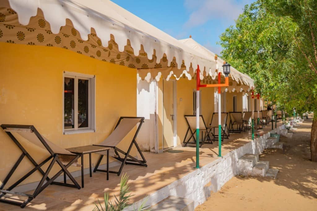 Daytime row of yellow camp cottages with lounge chairs outside each room