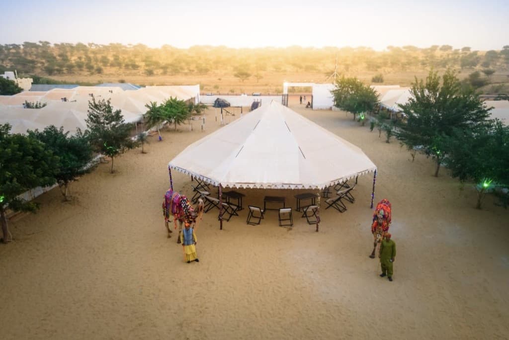 Aerial view of the Jaisalmer desert camp with decorated camels and a central tent