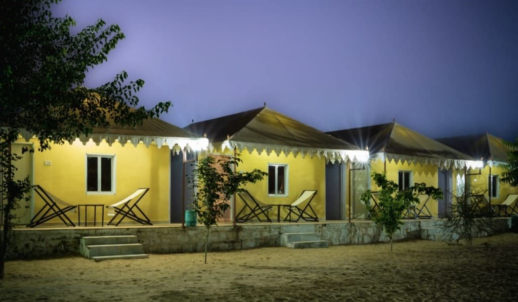 Yellow desert camp tents lit at night on the sand in Jaisalmer