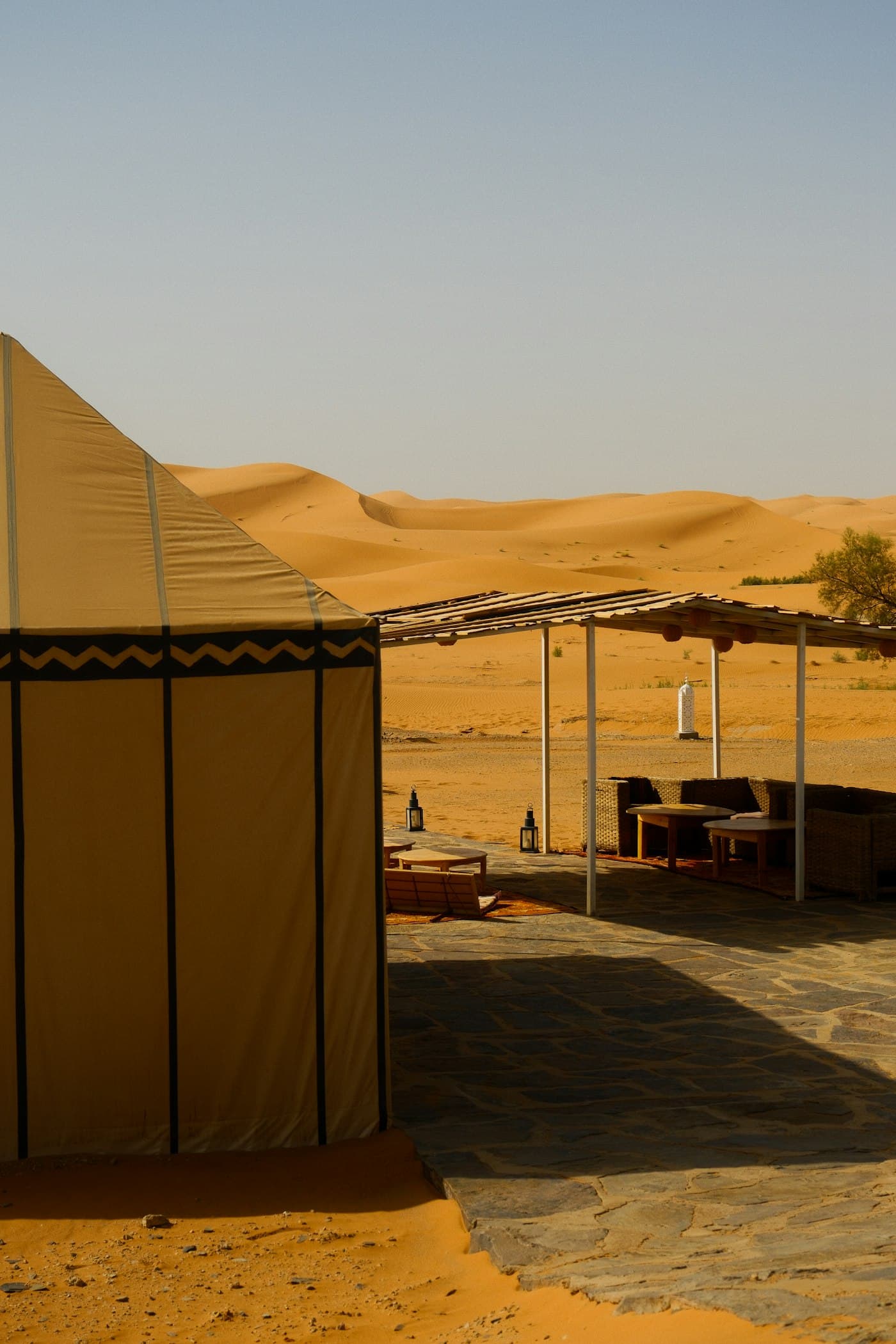 Luxury Swiss tent with outdoor seating facing sand dunes at a desert camp